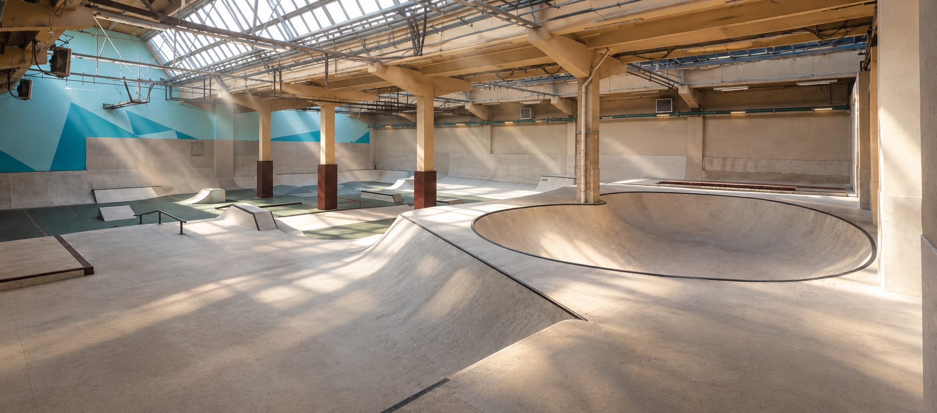 Kurazh 2.0, a 1,200 m² indoor skatepark in Moscow built by All-In Skate Parks: a concrete bowl flowing into wooden street sections under a skylight roof