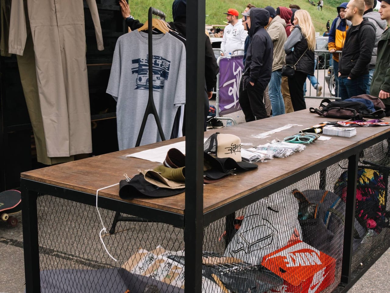 Clothing rail and counter inside the Anteater booth with the festival crowd behind