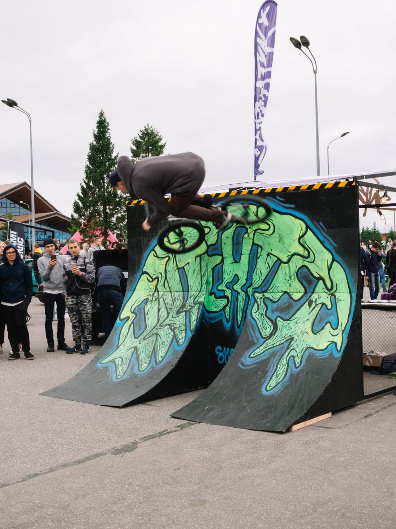 BMX rider airing over the graffiti quarter pipe on the back of the booth