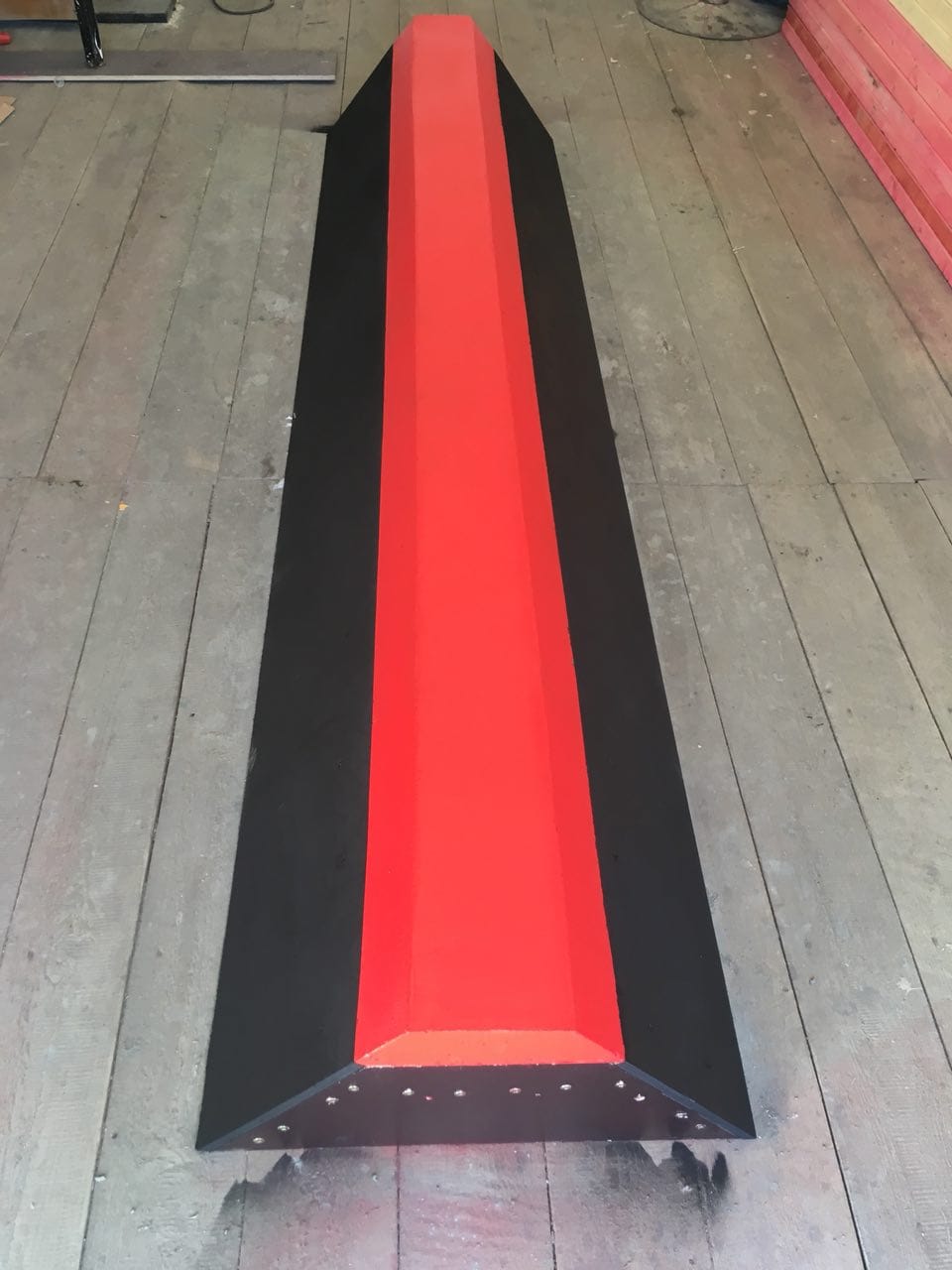 Black and red curb rail on a wooden floor