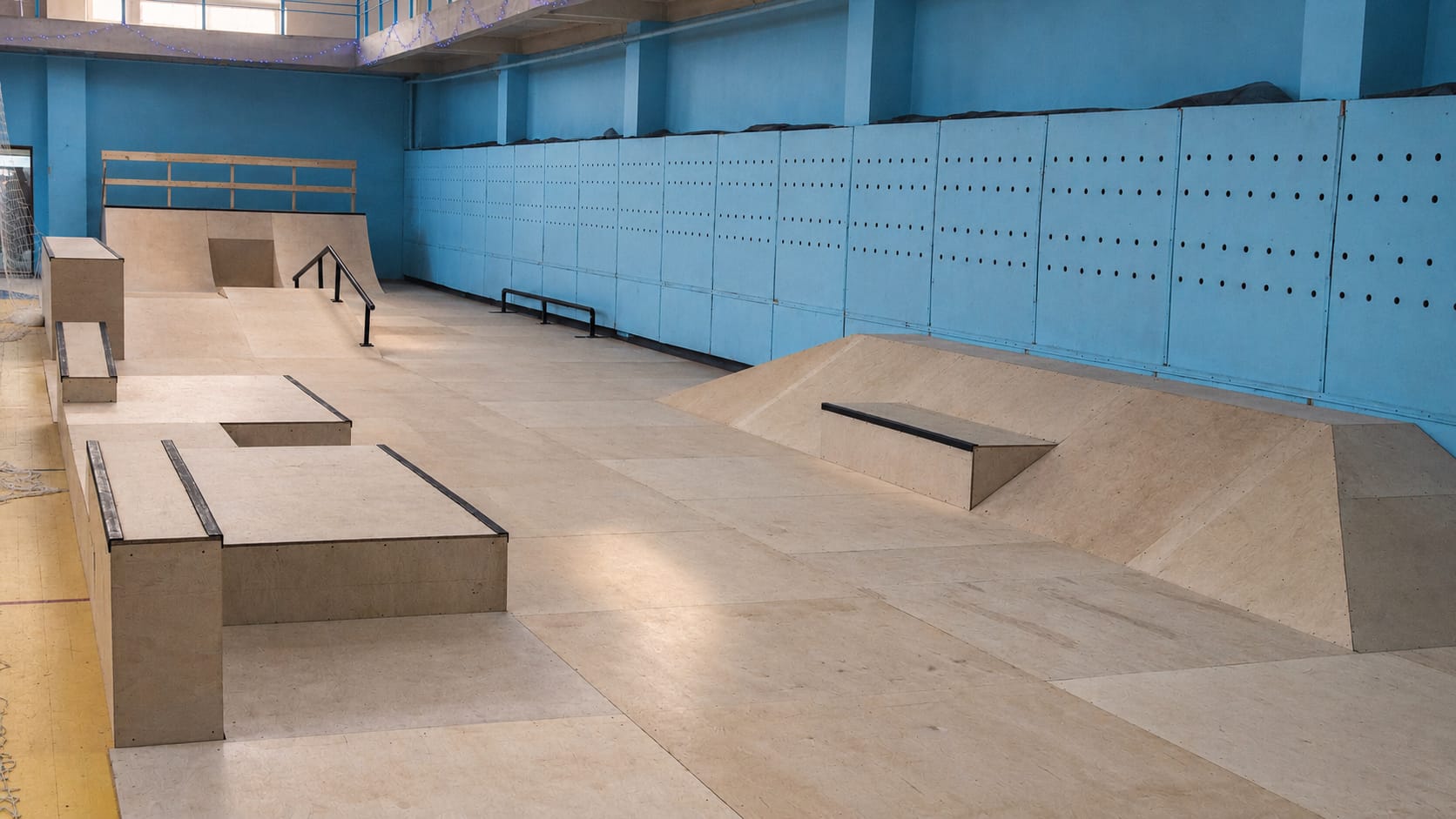 SPOT indoor skatepark in Omsk: wooden boxes, a ledge, a flat rail and a bank ramp in a blue sports hall