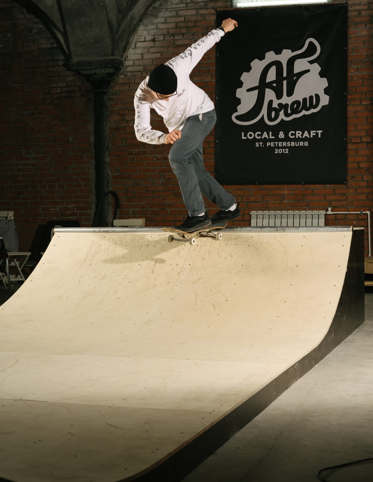 Skater riding the small ramp in front of the AF Brew banner