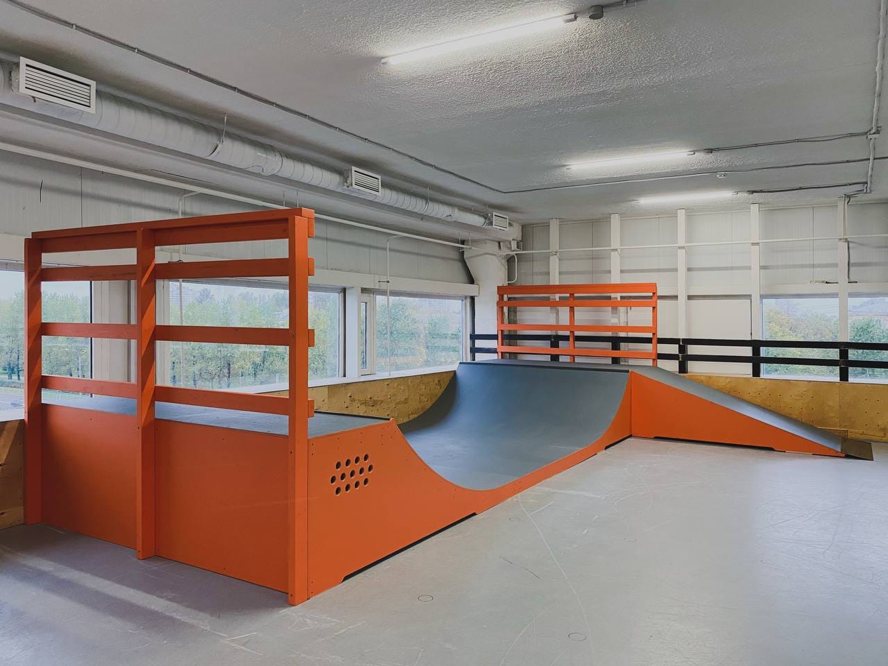 Indoor mini ramp with orange deck railings seen from the flat
