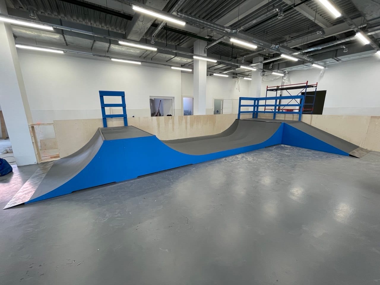 Blue mini ramp with a bank and deck railings in the Nogam Dorogu training hall