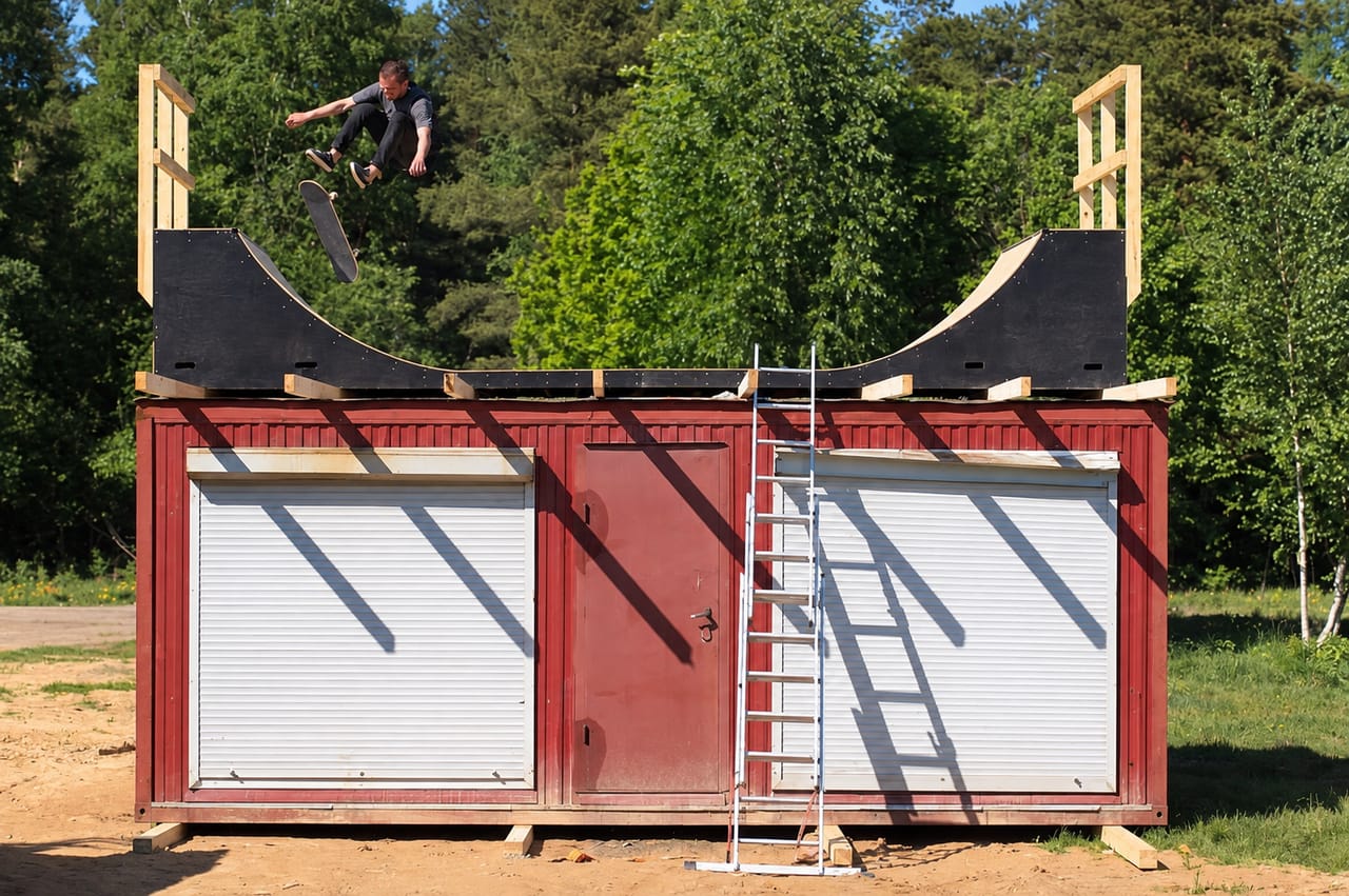 Skater airing out of the mini ramp built on the roof of a red storage building at a wake park