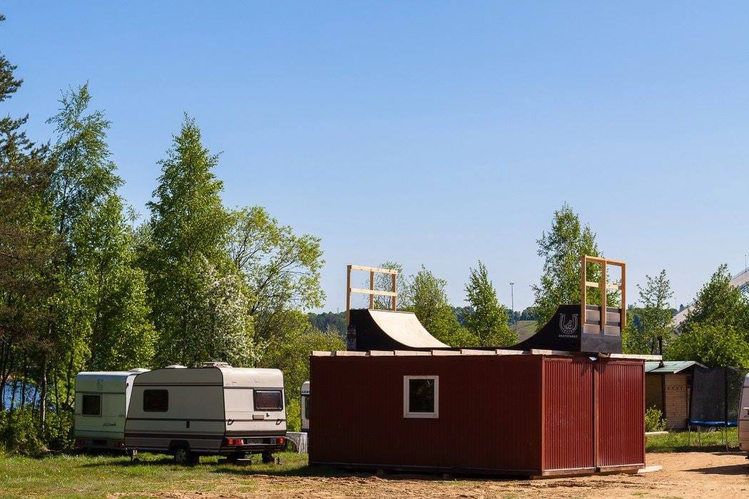 Wake park mini ramp on a red storage building among trees and caravans
