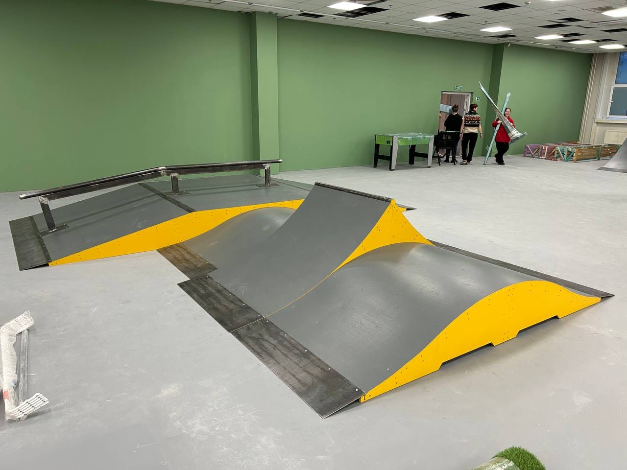 Grey and yellow funbox with a round rail and banks on a green-walled hall