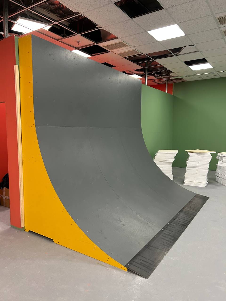 Tall curved wall with a yellow side panel at the end of the indoor street zone