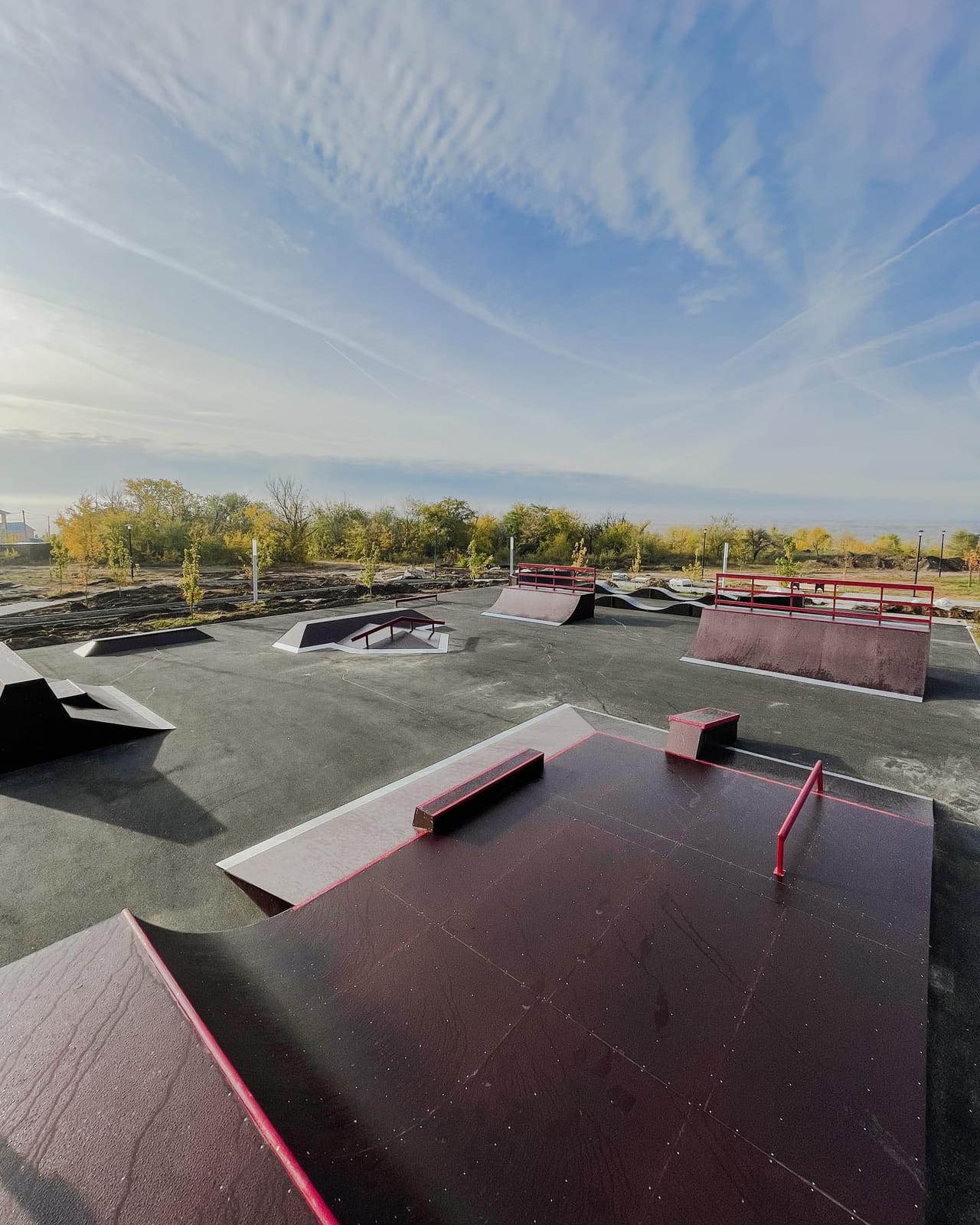 Ust-Donetsky outdoor skatepark overview: a funbox with red rails, banks and quarter pipes on an asphalt pad