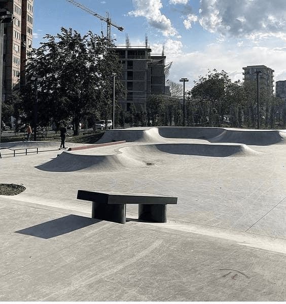Ground-level view of the Varketili concrete park with a black ledge in the foreground and riders in the background